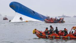 This photo taken at sea some 20 kilometres off the island of Byungpoong in Jindo on April 16, 2014 shows coast guard members searching for passengers near a South Korean ferry (C) that capsized on its way to Jeju island from Incheon.