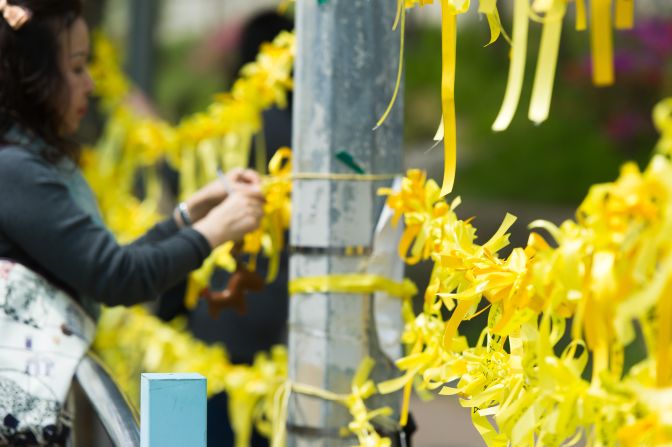 APRIL 24 - ANSAN, SOUTH KOREA: A woman ties <a href="http://cnn.com/2014/04/24/world/asia/south-korea-yellow-ribbons/index.html">yellow ribbons</a>, symbolizing hope for the safe return of missing passengers on the "Sewol" ferry, onto a main gate of Danwon High School. More than 300 students from the school were on a field trip on the ferry that sank last week off the coast of South Korea. 