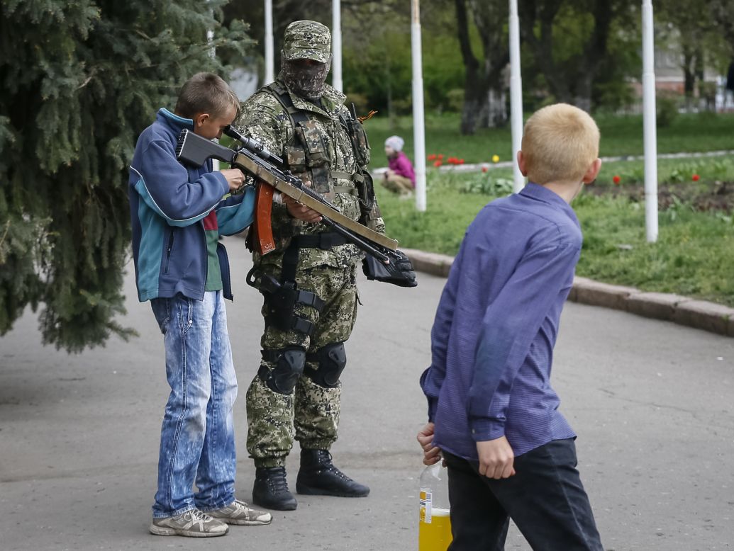 A boy looks through the scope on a machine gun as a pro-Russian armed man stands guard outside the mayor's office in Slaviansk, Ukraine, on Sunday, April 20. 