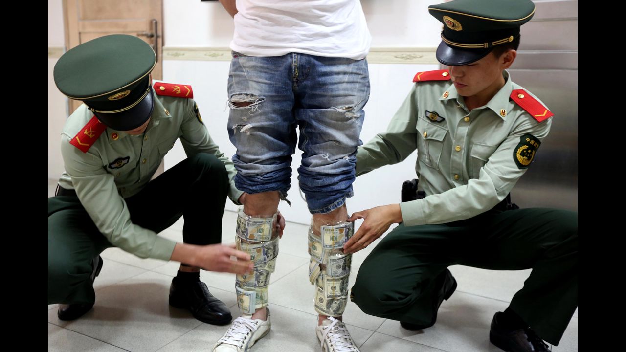 Officers reveal U.S. banknotes strapped to the legs of a man at a checkpoint in the Chinese city of Shenzhen on Wednesday, April 23. The man hid around $580,000 in excess cash.