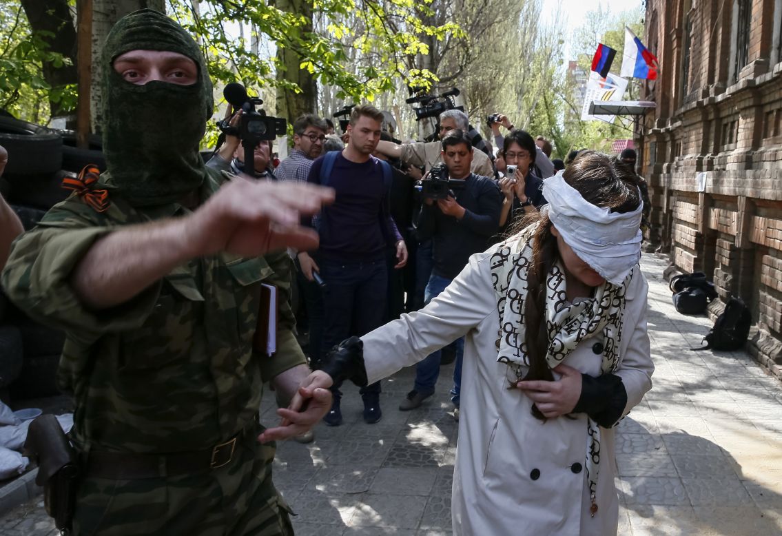 A pro-Russian armed man escorts Ukrainian journalist Irma Krat after news conference in Sloviansk, Ukraine, on Monday, April 21. Ukraine has seen a sharp <a href="http://www.cnn.com/2014/03/26/world/gallery/ukraine-crisis/index.html">rise in tensions</a> since a new pro-European government took charge of the country in February.