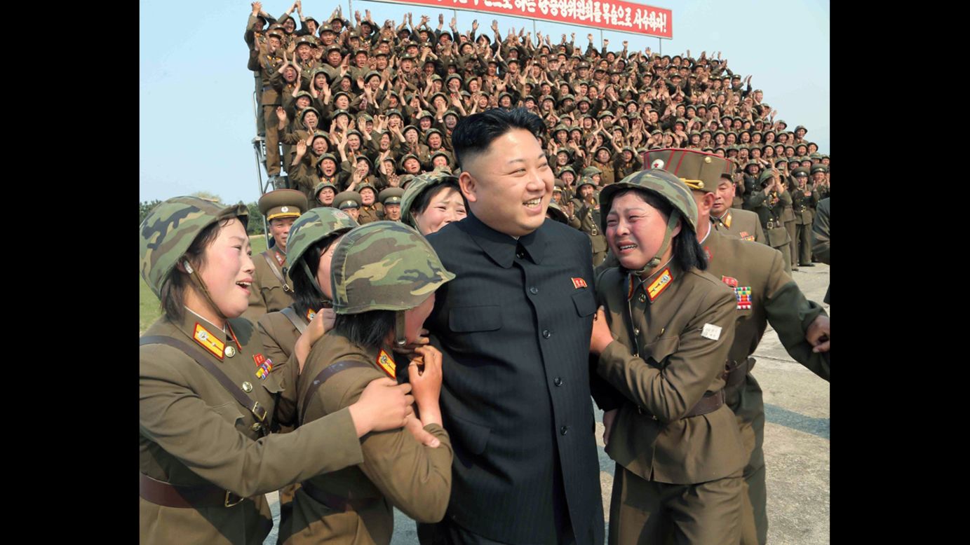 North Korean leader Kim Jong Un smiles with female soldiers after inspecting a multiple-rocket launching drill at an undisclosed location. The undated photo was released on Thursday, April 24, by North Korea's official Korean Central News Agency.