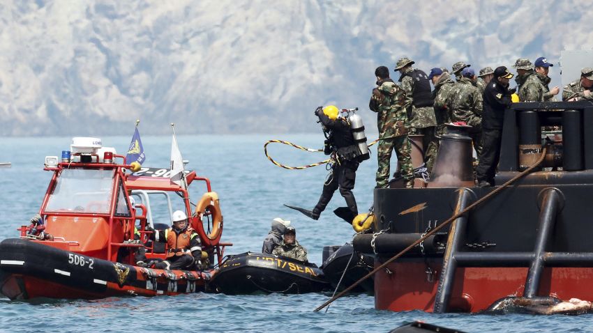 A diver jumps into the sea to look for people believed to have been trapped in the sunken Sewol ferry near buoys which were installed to mark the vessel in the water off the southern coast near Jindo, South Korea, Friday, April 25, 2014. Frustrated relatives of the scores of people still missing from the sinking of the ferry staged a marathon confrontation with the fisheries minister and the coast guard chief, surrounding the senior officials in a standoff that lasted overnight and into Friday morning as they vented their rage at the pace of search efforts.(AP Photo/Yonhap) KOREA OUT