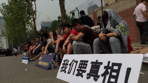 Around 100 relatives of MH370 passengers protest outside the Malaysian Embassy