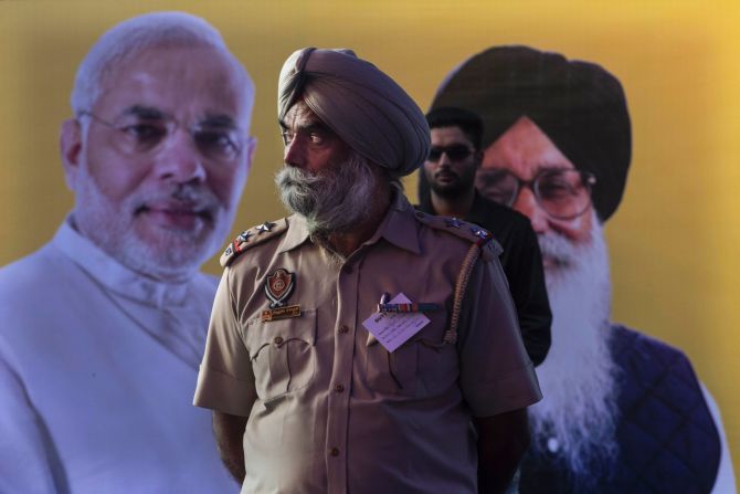 An Indian Punjab State Police officer stands in front of a picture of Bharatiya Janata Party leader Narendra Modi and Punjab Chief Minister Parkash Singh Badal during an election rally by the two men April 25 in Bathinda, India.