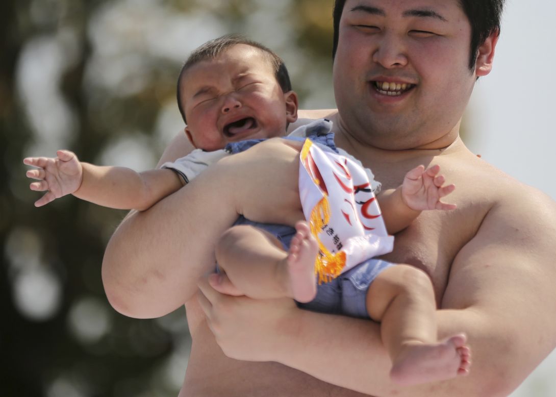 Held by an amateur sumo wrestler, a baby cries during <em>naki-zumo</em> (crying baby contest) at Sensoji Buddhist temple in Tokyo, Saturday, April 26. The contest celebrates a traditional belief that a baby who cries grows more quickly.