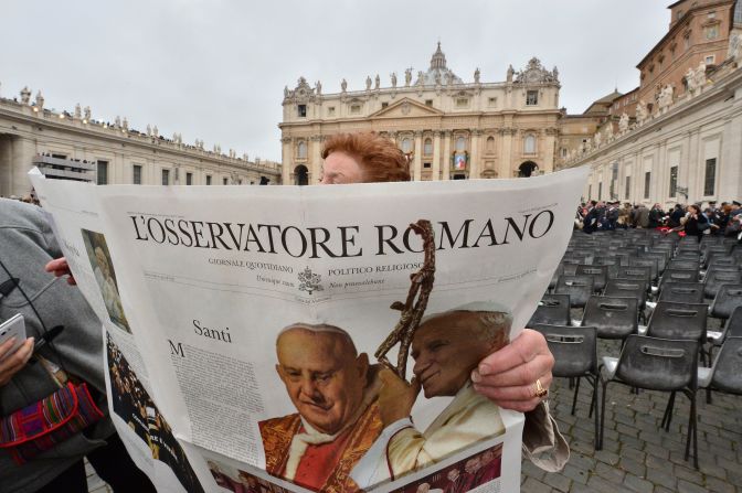 A woman reads a newspaper before the start of the canonization Mass on April 27.