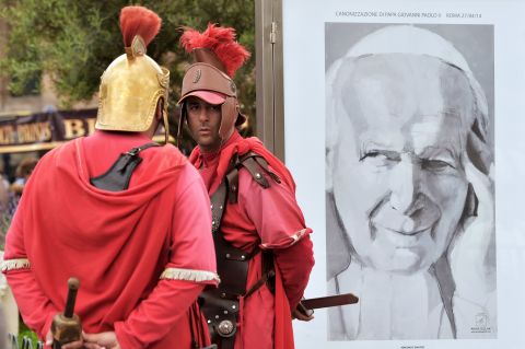 Men dressed as centurions stand by a portrait of Pope John Paul II in Rome during the canonization Mass on April 27.