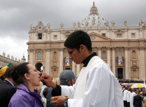 A priest gives Holy Communion to a woman in St. Peter's Square at the Vatican on April 27.