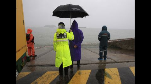 A police officer holds an umbrella for a relative of a missing ferry passenger Monday, April 28, in Jindo, South Korea.