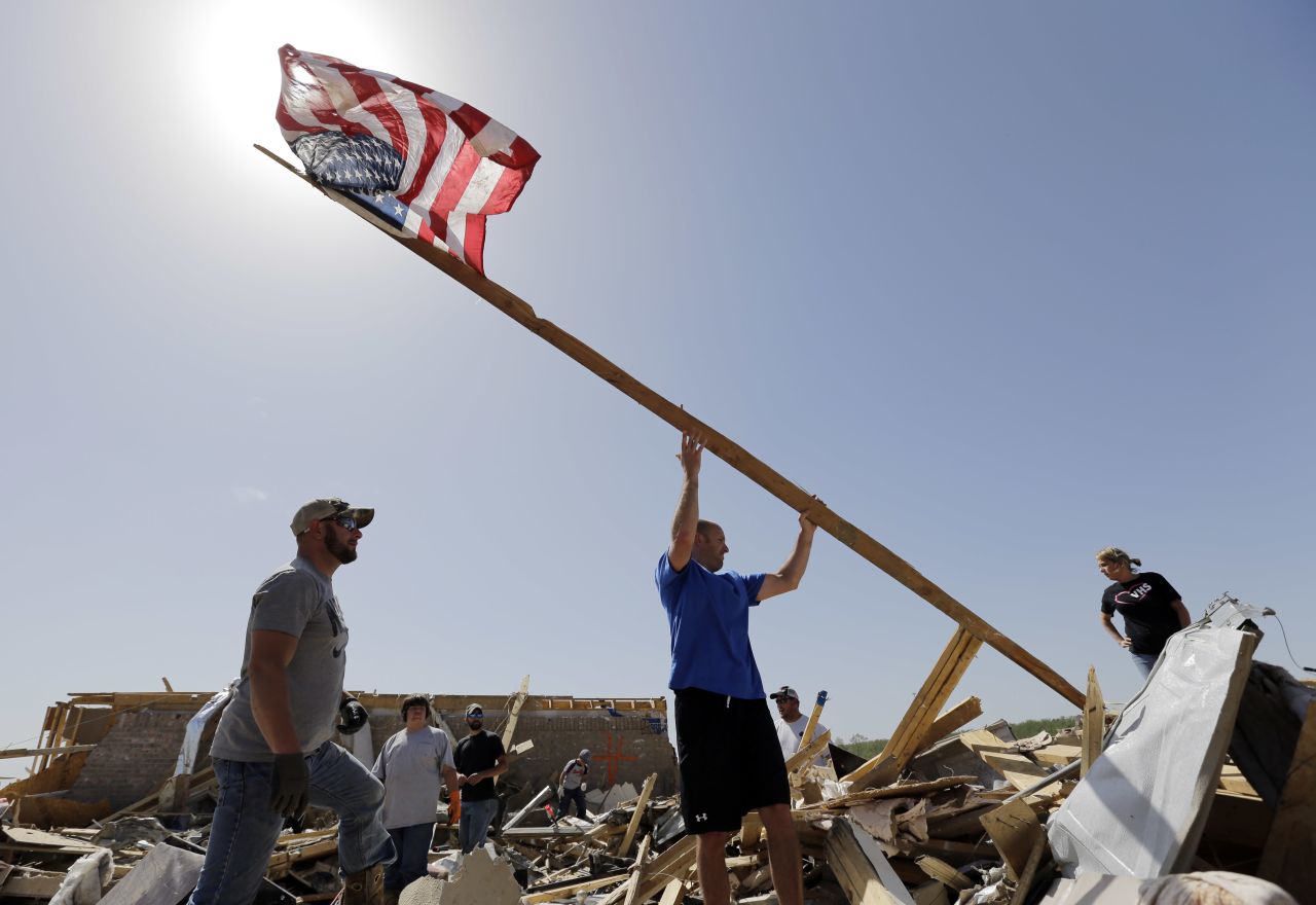 Justin Shaw, left, helps Nick Conway erect a flagpole April 28 at his destroyed home in Vilonia.