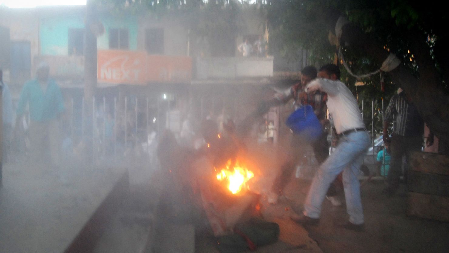 Indian bystanders attempt to douse the blaze as a local politician and a man are engulfed in flames.