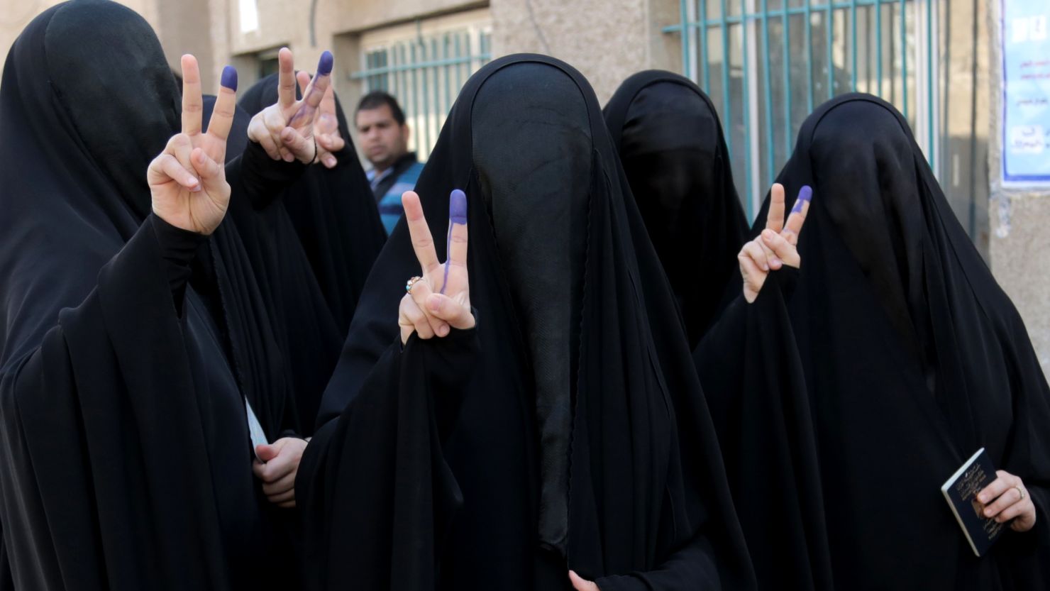 Iraqi women give victory signs while showing their inked fingers after voting in Baghdad on Wednesday. 