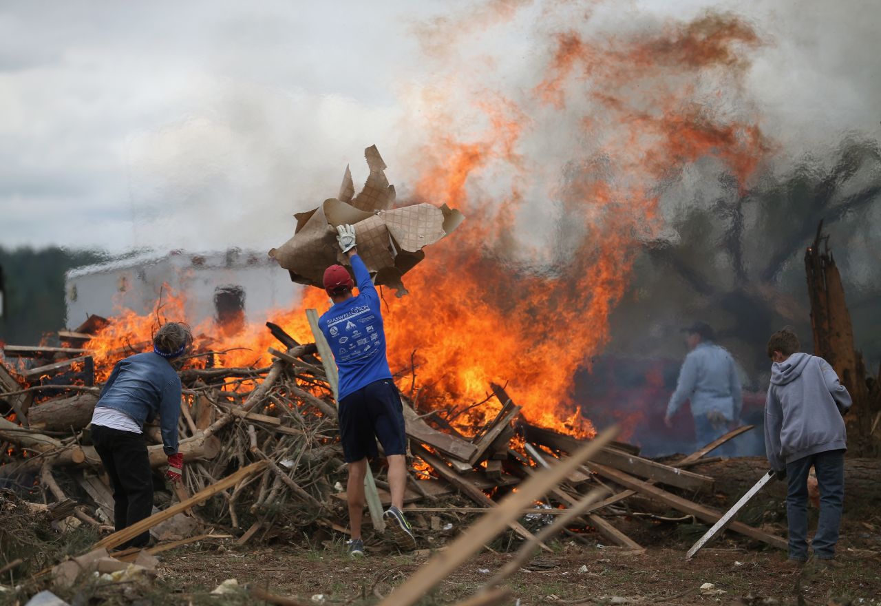 Volunteers throw tornado debris on a burn pile in Vilonia, Arkansas, on April 30.
