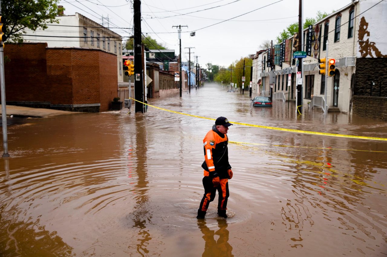 Police officer Robert Jonah walks through floodwaters in the Manayunk neighborhood of Philadelphia on Thursday, May 1. A powerful storm system, including a series of tornadoes, has claimed at least three dozen lives in several states this week.