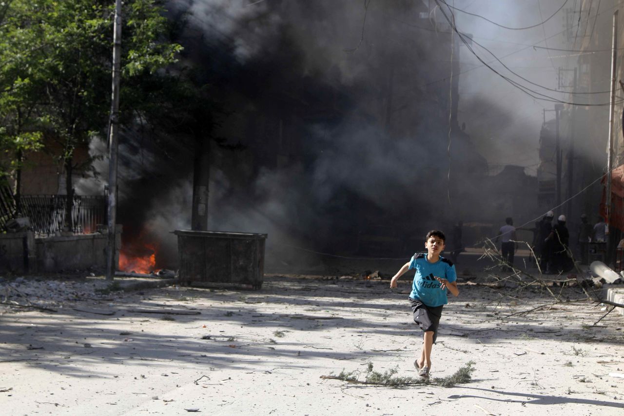 A boy runs in Aleppo on Sunday, April 27, after what activists said were explosive barrels thrown by forces loyal to al-Assad.