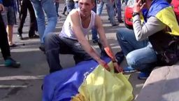 TV images released by INTER, shows a man covering the bloodied body of a man with an Ukrainian flag during a demonstration on May 2, 2014 in Odessa.