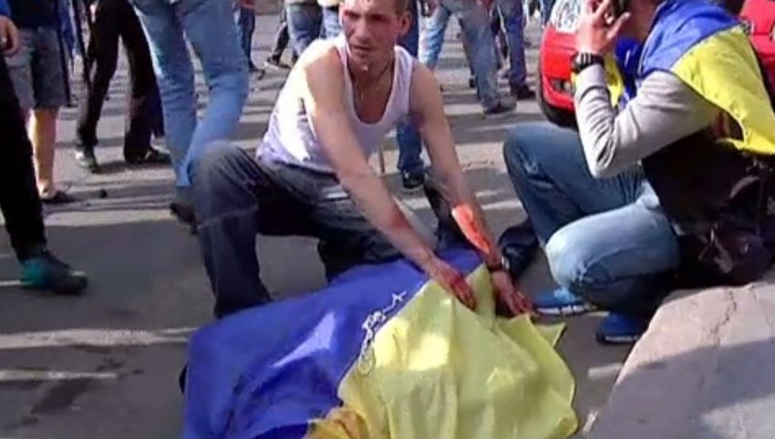 TV images released by INTER, shows a man covering the bloodied body of a man with an Ukrainian flag during a demonstration on May 2, 2014 in Odessa. 