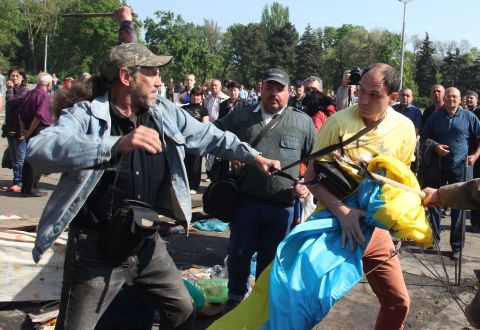 Pro-Russian activists beat a pro-Ukraine supporter trying to save the Ukrainian flag that was removed from a flagpole outside the burned trade union building in Odessa.