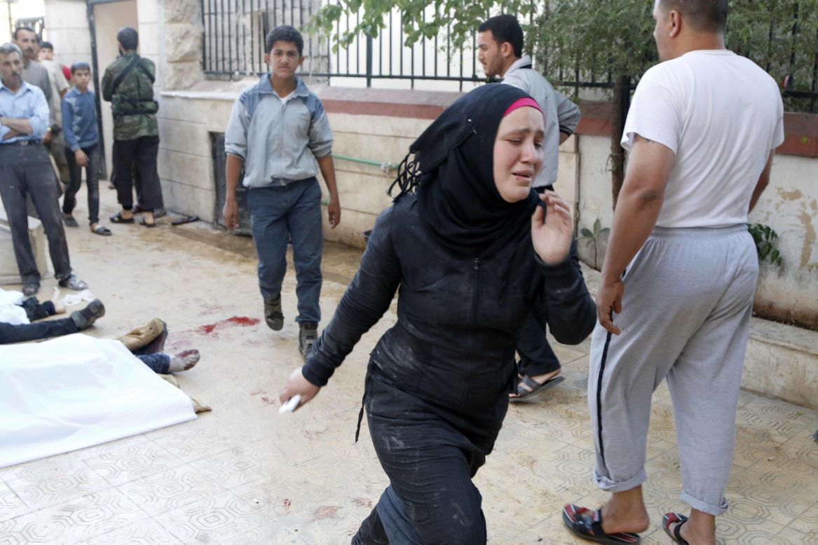 A woman runs after two barrel bombs were thrown, reportedly by forces loyal to Syrian President Bashar al-Assad in Aleppo on May 1.