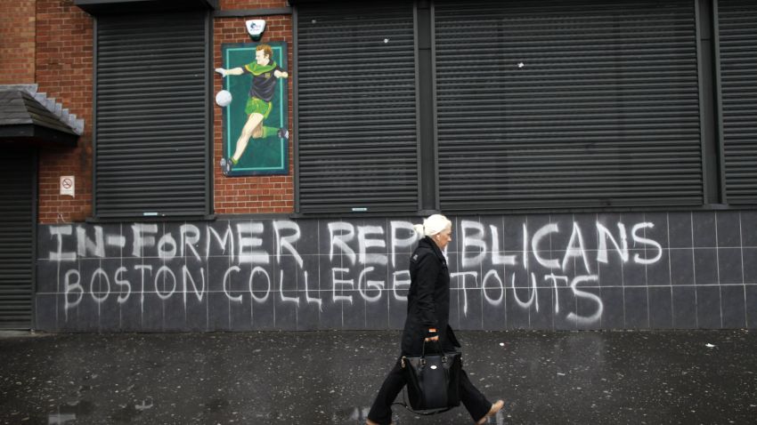A woman passes graffiti on the Falls Road referring to former Republicans who took park in the Boston college tape recordings in West Belfast, Northern Ireland on May 4, 2014. Tensions in Northern Ireland rose on May 3 after police obtained an extension to question detained republican leader Gerry Adams over a notorious IRA murder. In 2001, Boston College, a prestigious Catholic institution, researchers embarked on a project to interview participants in the Northern Ireland conflict known as the Troubles. They set about constructing an oral history of the violent period, interviewing dozens of former Irish Republican Army members and participants in voluntary paramilitary groups that supported union with Britain. Interviewees were promised absolute anonymity until after their deaths. That guarantee unraveled amid court orders, with potentially serious consequences for participants in Ireland, and fresh questions about academic freedom and the strength of researchers' confidentiality assertions in the face of a criminal investigation. "Boston College sold us out, " Belfast Project founder and journalist Ed Moloney told AFP, saying the school capitulated almost immediately when court officials demanded the recordings. . AFP PHOTO / PETER MUHLYPETER MUHLY/AFP/Getty Images