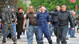 Pro-Russian militiants carry an man with his eyes covered outside the regional state building they seized in the eastern Ukrainian city of Donetsk on May 5, 2014.