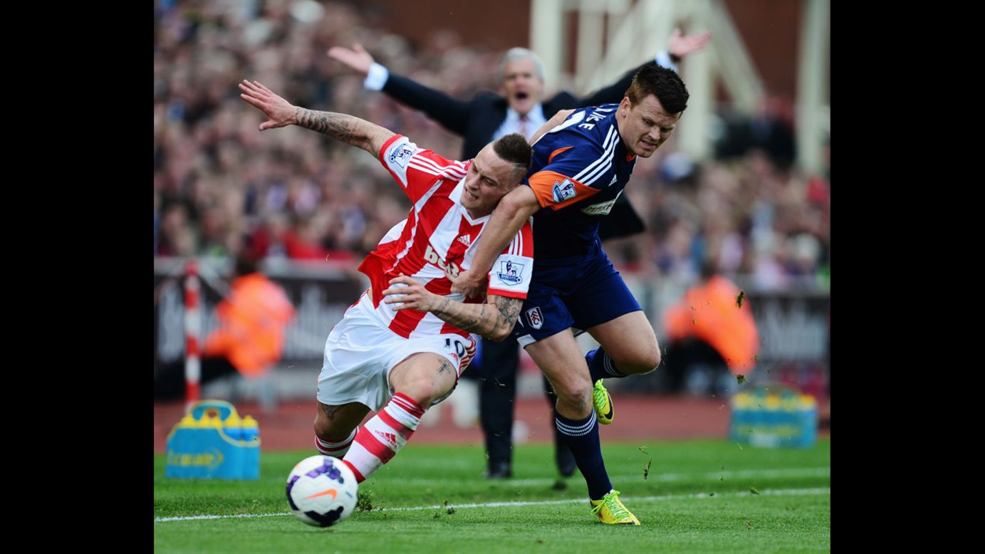 Marko Arnautovic of Stoke City, left, and John Arne Riise of Fulham challenge for the ball Saturday, May 3, as Stoke City manager Mark Hughes appeals in the background. Stoke City won the match 4-1, and the result meant that Fulham would be relegated from the English Premier League after a 13-year stay.