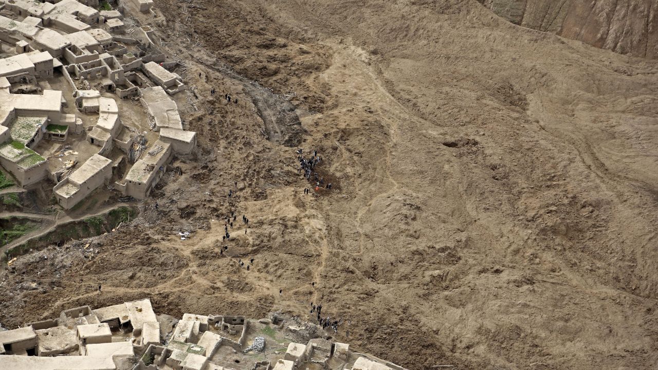 Afghans walk near the site of the landslide on May 5. 