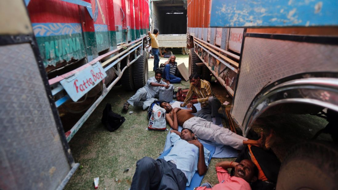 Election officers rest between parked trucks before proceeding to their polling stations May 6 in Allahabad, India.