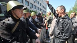 Pro-Russian supporters demonstrate in front of Ukrainian policemen guarding the entrance of a state city building in Mariupol on May 7, 2014.