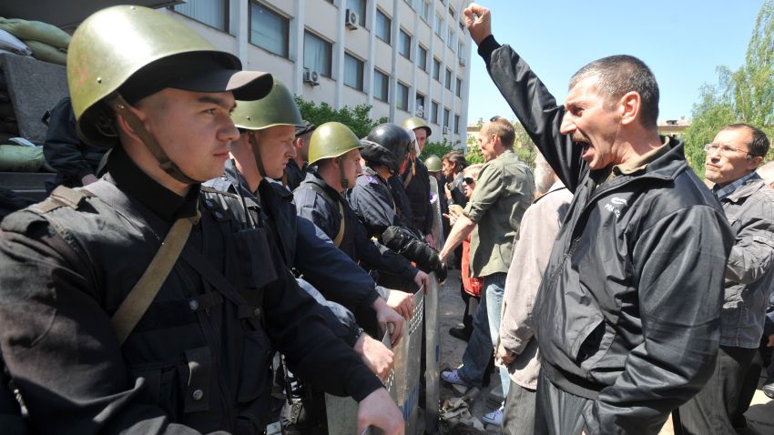 Pro-Russian supporters demonstrate in front of Ukrainian policemen guarding the entrance of a state city building in Mariupol on May 7, 2014.