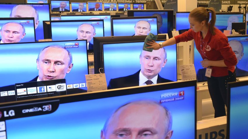 An employee wipes a TV screen in a shop in Moscow, on April 17, 2014, during the broadcast of President Vladimir Putin's televised question and answer session with the nation.