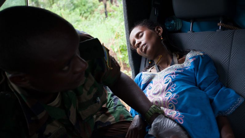 A man tends to a woman in labor along the road near Sibut, Central African Republic. She was one of three women who gave birth to five babies during the journey.