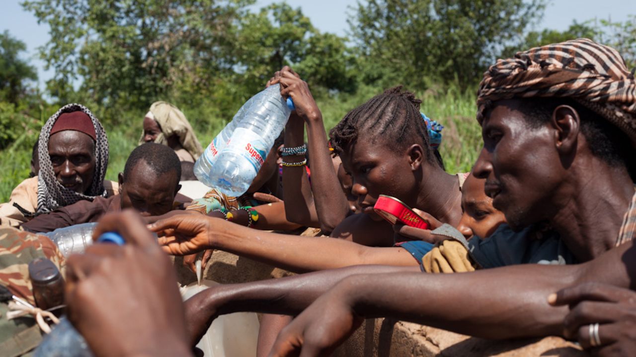 Despite security risks, refugees break away from the group to collect water from a nearby well, after the convoy ran out on the third day of the journey.