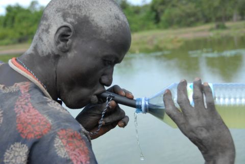A Southern Sudanese man uses a pipe filter to strain possible water fleas, which could contain Guinea worm larvae, from a potentially contaminated water source.