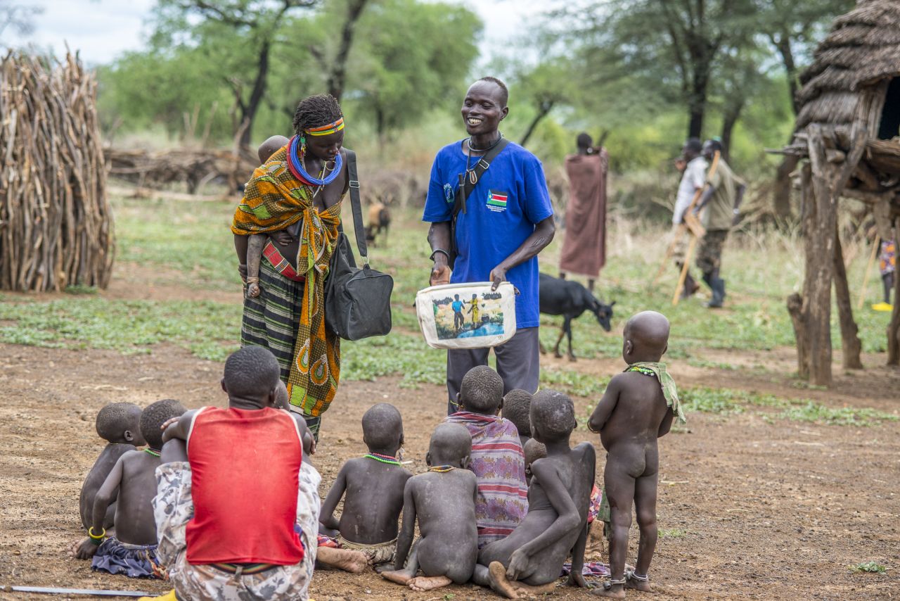 In South Sudan, area supervisor Paulo Lovul and village volunteer Aleper Akol Naparinga use visual aids such as picture books to teach people how to avoid contracting Guinea worm.