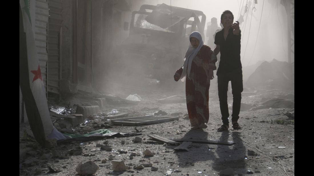 A man helps a woman through debris after reported airstrikes by government forces on Thursday, May 1, in the Halak neighborhood of Aleppo. 