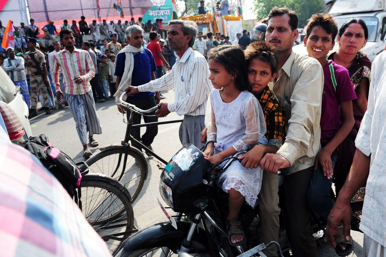 A family on a motorcycle passes Indian National Congress supporters in Varanasi on May 10.