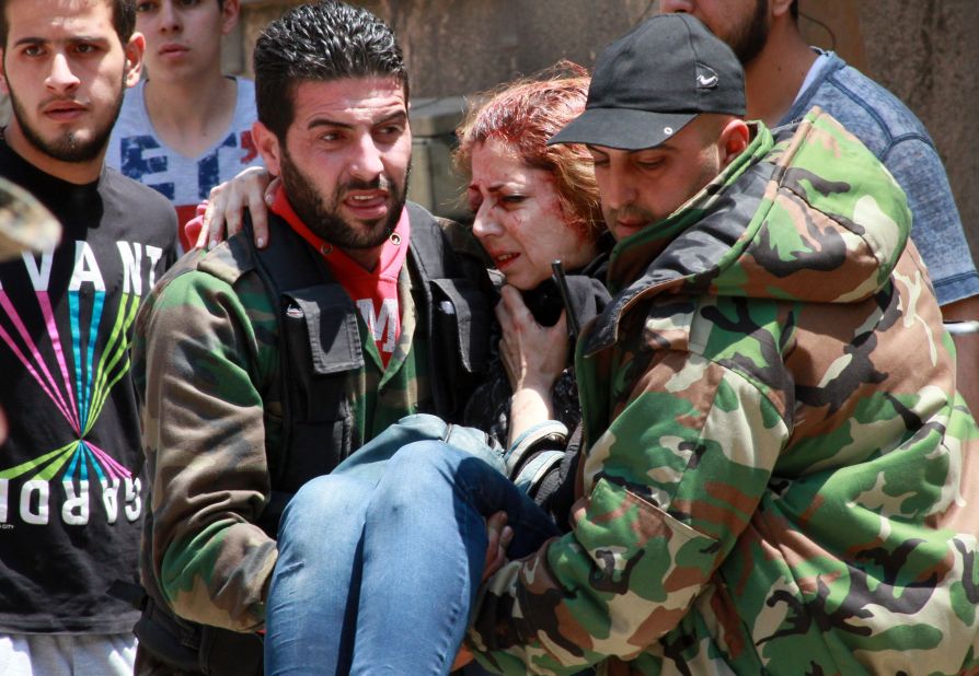 A woman injured when a mine went off is carried in Homs on May 10.