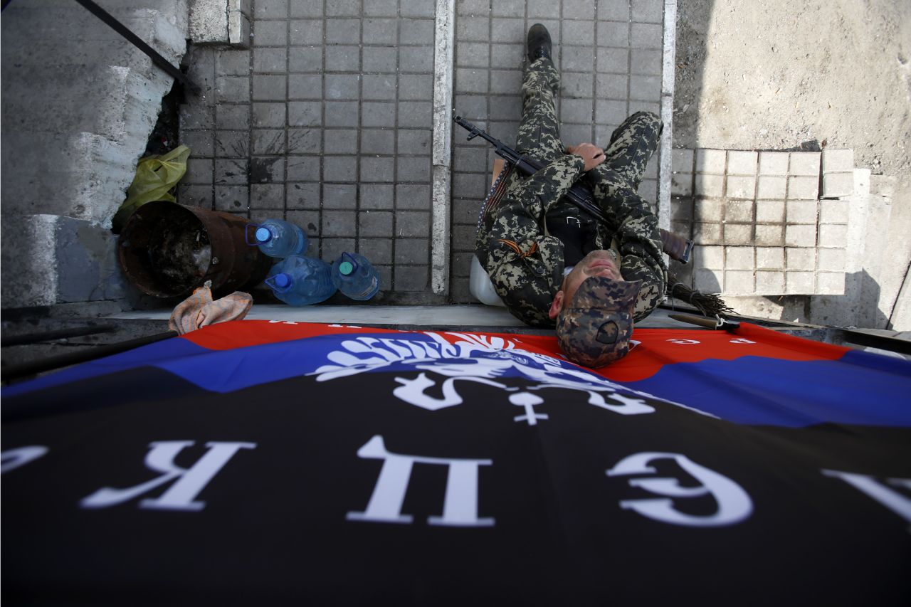 An armed pro-Russian man sits below a flag of the self-proclaimed Donetsk People's Republic at the barricades on a road leading into Slovyansk on May 11. 
