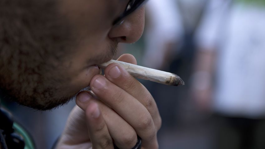 A man smokes a joint during a march for the legalization of marijuana towards the Legislative Palace in Montevideo, on December 10, 2013, as the Senate discuss a law on the legalization of marijuana's cultivation and consumption.