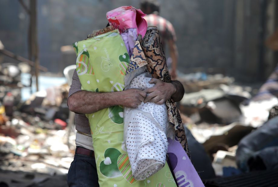 A man carries rolls of cloth out from a destroyed building in Homs on May 12. 