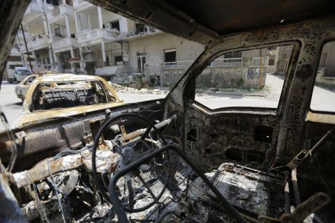 Destroyed vehicles line the streets of Homs on May 12.