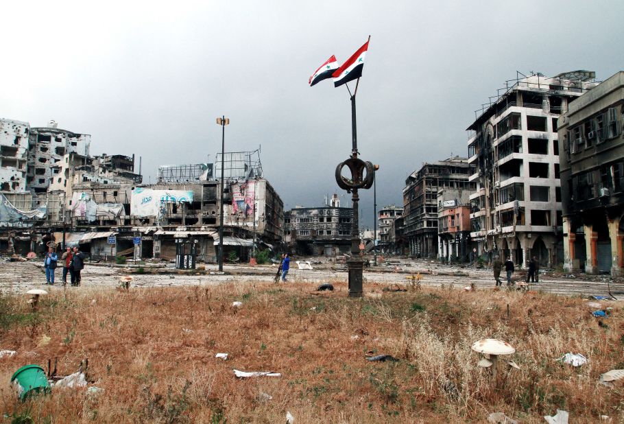 Two Syrian national flags fly overhead as government officials inspect the streets of war-torn Homs on Thursday, May 8, after the rebels withdrew from their remaining strongholds in the heart of the city.