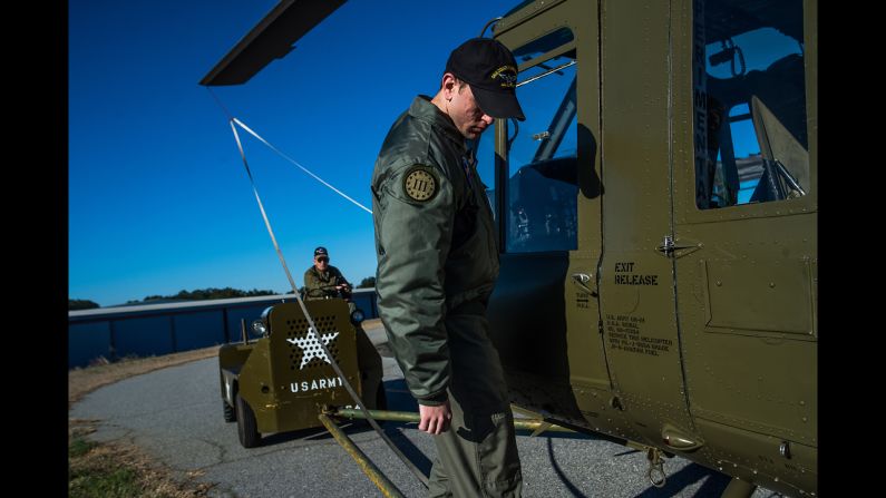 Foundation volunteer Tyler Phillips hops aboard a restored Huey helicopter as it is towed from the hangar to the tarmac in preparation for flight in Hampton. 