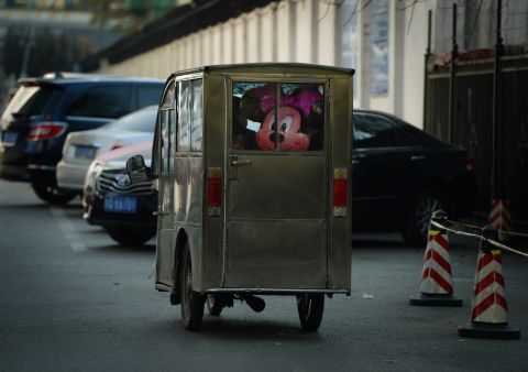 But not everyone is enchanted by the motorized rickshaws, as many see them as a relic of the past and as a traffic-congesting and pollution-emitting nuisance. This shows a Minnie Mouse in the back of a Chinese motorcycle taxi. 