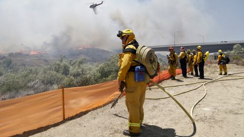 Firefighters watch from a ridge as a helicopter drops retardant on flames in San Diego on May 13.