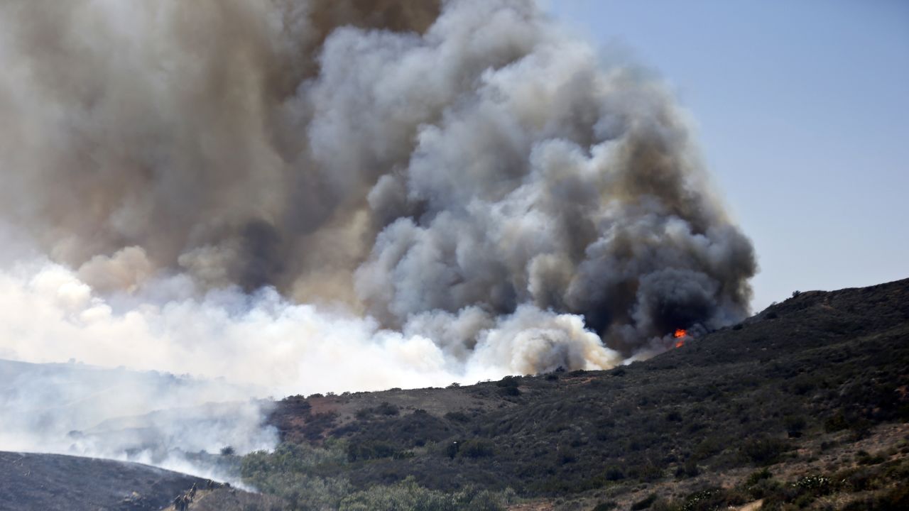 Billowing smoke rises as firefighters trek up the hills to battle a San Diego fire on May 13.
