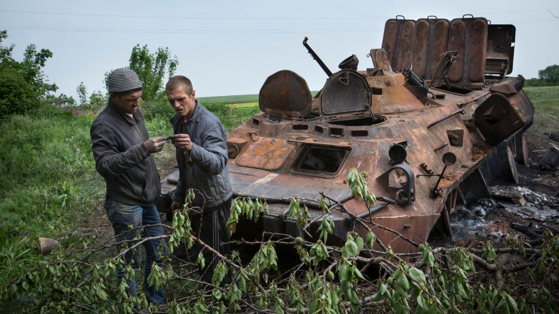 Two men collect parts of a Ukrainian armored personnel carrier, destroyed May 14 in what the Ukrainian Defense Ministry called a terrorist attack near Kramatorsk.