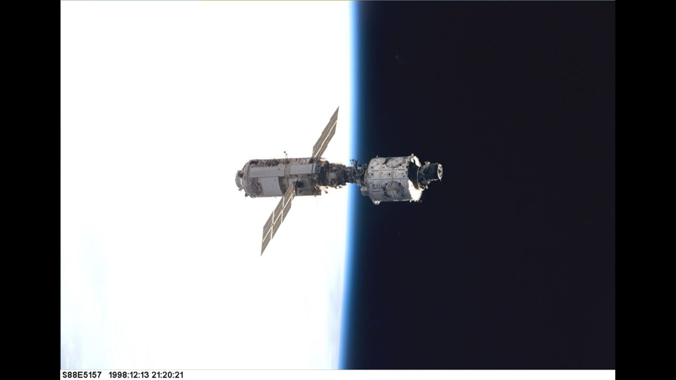 The Zarya control module, on the left with the solar panels, floats above Earth with its newly attached Unity module after the first assembly sequence in December 1998.
